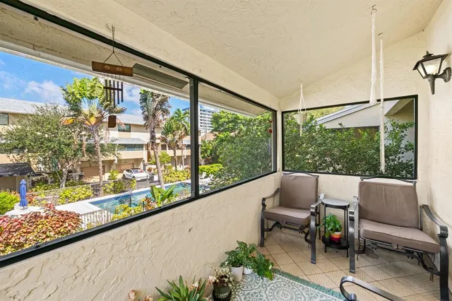 a balcony with couple of chairs and a potted plant