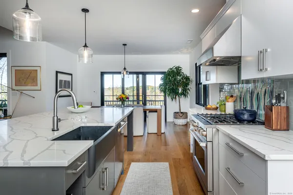 a kitchen with stainless steel appliances granite countertop a sink a stove and a wooden floors