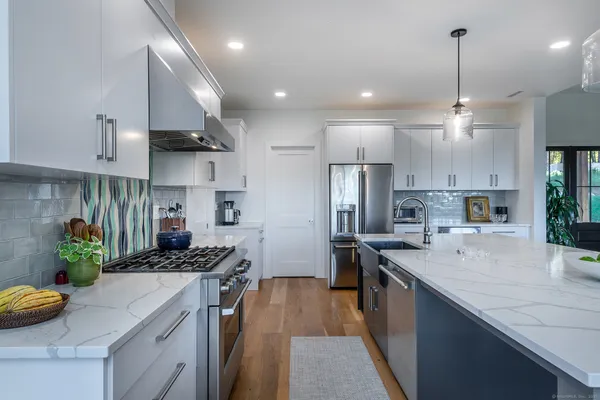 a kitchen with kitchen island granite countertop a sink a counter top space appliances and cabinets