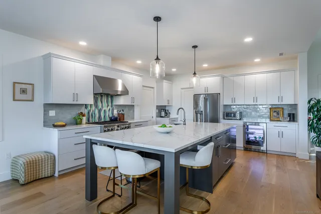 a kitchen with stainless steel appliances kitchen island granite countertop a table chairs and a refrigerator
