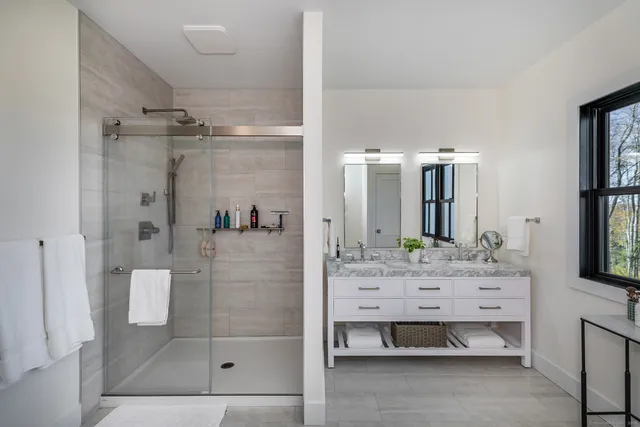 a bathroom with a double vanity sink mirror and shower