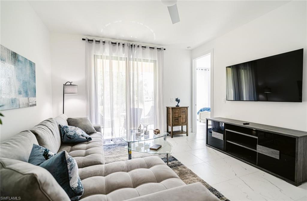 907 Homestead Road South Lehigh Acres, FL 33974 - Photo 14 of 43 Bright living area featuring white walls, large sliding glass doors with sheer curtains, and light-toned tile flooring