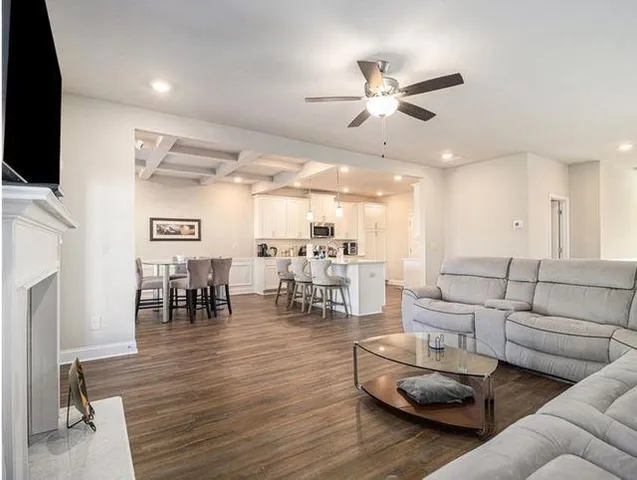 a living room with furniture and a flat screen tv with kitchen view