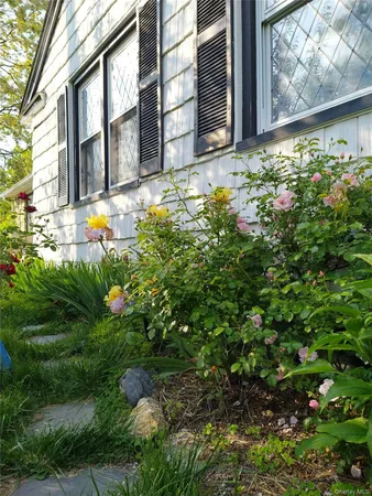 a view of yellow house with a yard and sitting area
