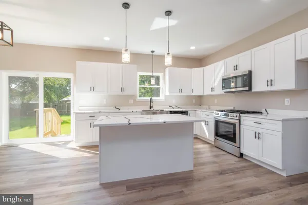 a kitchen with kitchen island granite countertop a stove a sink a center island and cabinets