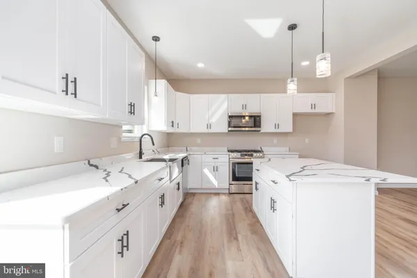 a large white kitchen with a sink a stove a refrigerator cabinets and a window