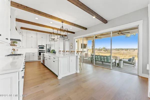 a living room with lots of furniture kitchen view and a large window