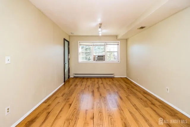 an empty room with wooden floor and windows
