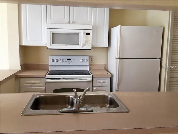 a kitchen with a refrigerator sink and cabinets