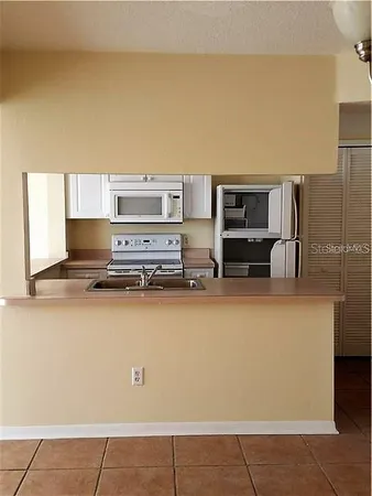 a living room with stainless steel appliances furniture a kitchen view and a refrigerator