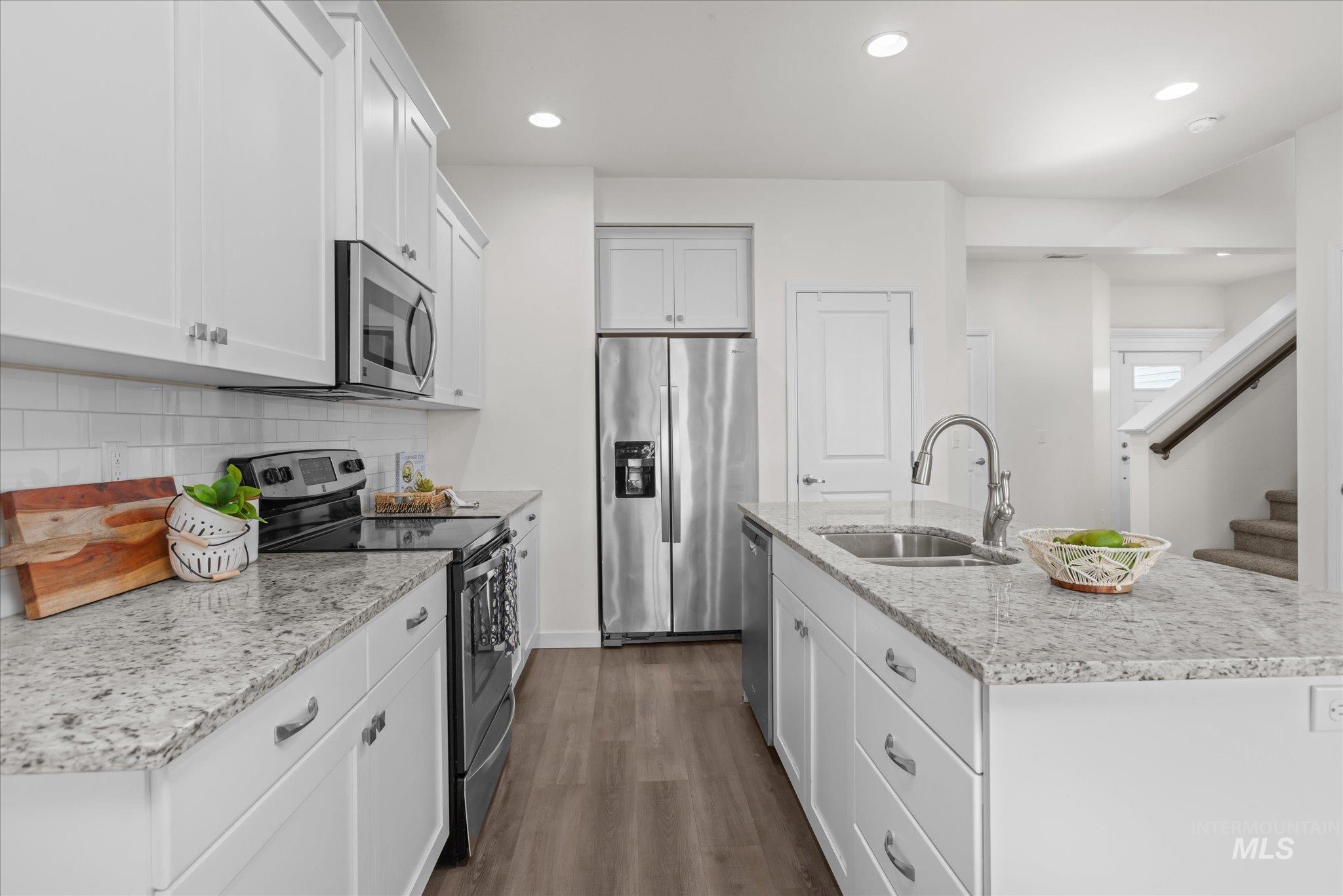 1885 North Justin Avenue Meridian, ID 83646 - Photo 12 of 27 Kitchen featuring stainless steel appliances, a center island with sink, dark wood-style flooring, recessed lighting, and light stone counters