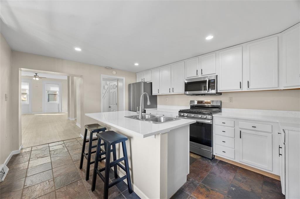 1312 Boyle Street Pittsburgh, PA 15212 - Photo 20 of 50 a kitchen with stainless steel appliances kitchen island a table chairs sink and cabinets