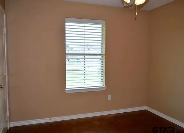an empty room with a window and a fan