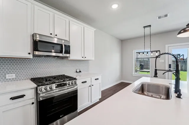 a kitchen with granite countertop a sink a stove and microwave