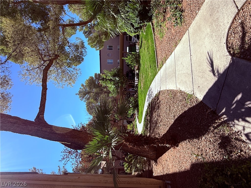 9325 West Desert Inn Road, Unit 260 Las Vegas, NV 89117 - Photo 29 of 42 A winding concrete path gracefully guides through vibrant landscaping under a clear sky.