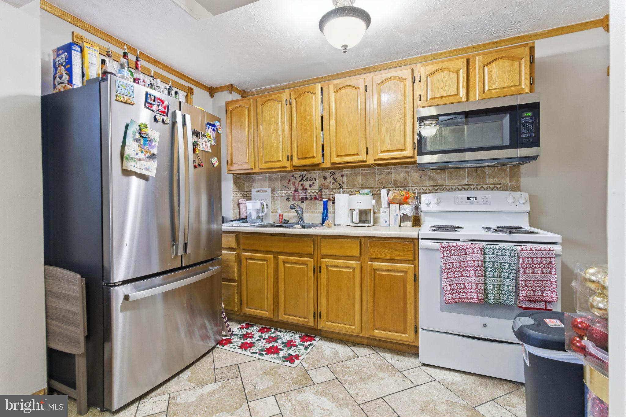 4524 Robbins Street Philadelphia, PA 19135 - Photo 7 of 26 a kitchen with stainless steel appliances a refrigerator and cabinets