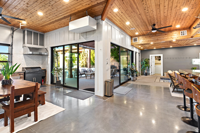 912 North Loafer Canyon Road Elk Ridge, UT 84651 - Photo 21 of 98 Wood-paneled ceilings with exposed beams, polished concrete flooring, extensive sliding glass doors, built-in kitchen area with white subway tile backsplash, and a large bar with built-in seating