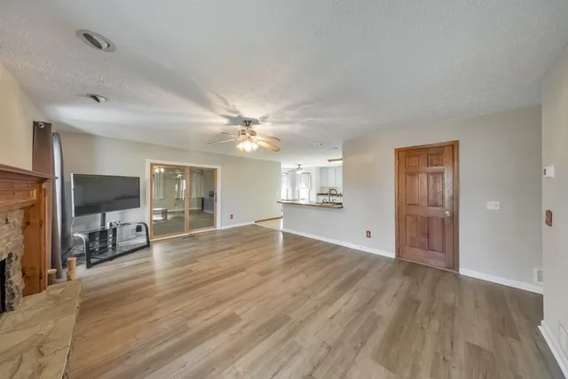 a view of a livingroom with a flat screen tv wooden floor and a ceiling fan