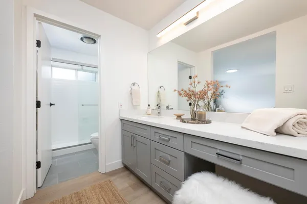 a spacious bathroom with a double vanity sink a mirror and a shower