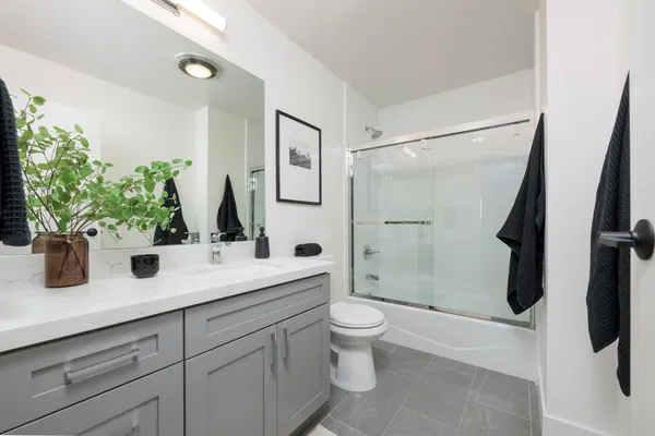 a bathroom with a granite countertop sink a toilet a mirror and shower