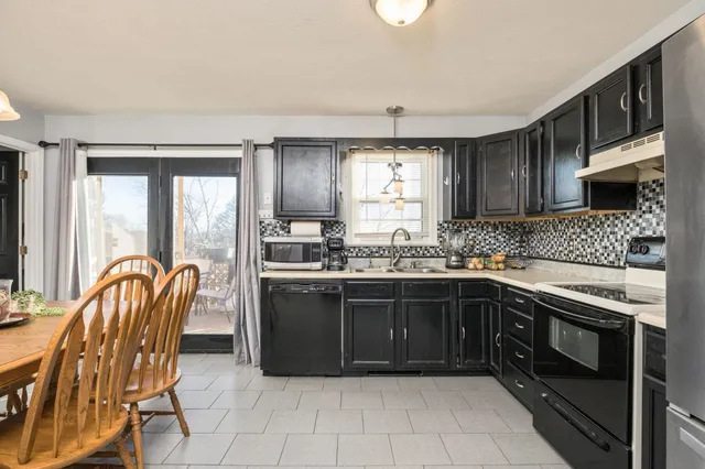 a kitchen with stainless steel appliances granite countertop a stove top oven a sink dishwasher a dining table and chairs with wooden floor