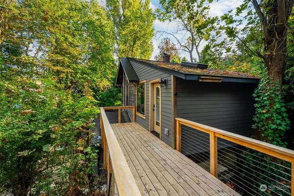a view of house with wooden deck and trees
