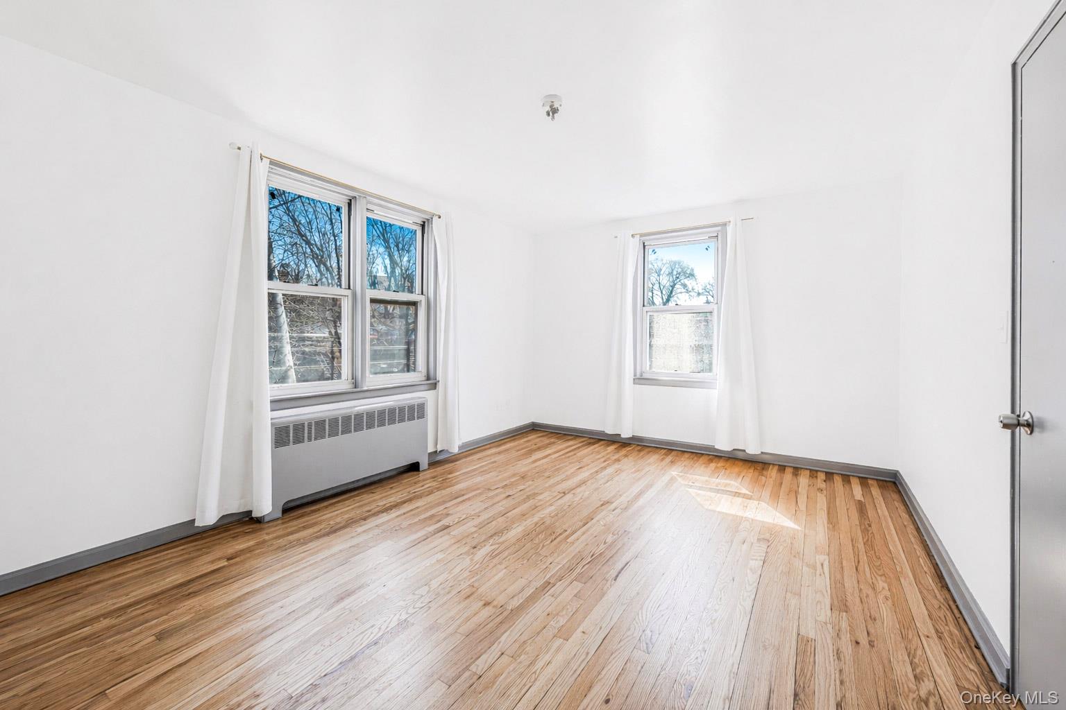 150 Ravine Avenue, Unit 3B Yonkers, NY 10701 - Photo 7 of 9 a view of an empty room with wooden floor and windows