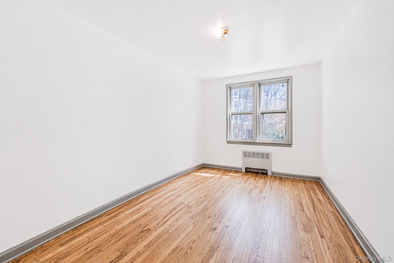 150 Ravine Avenue, Unit 3B Yonkers, NY 10701 - Photo 8 of 9 an empty room with wooden floor and windows