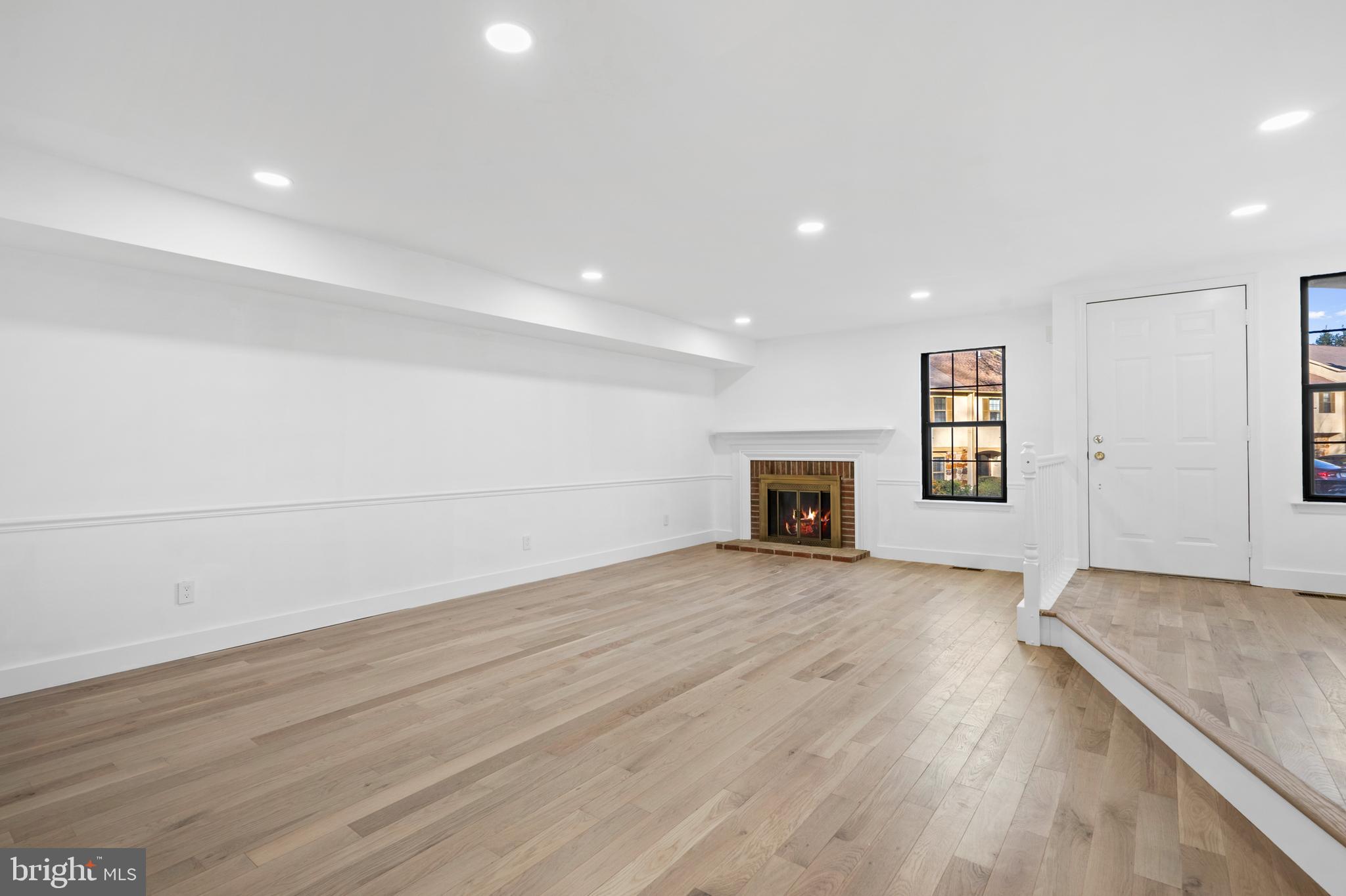 1007 Stoneham Drive, Unit 1007B Newtown Square, PA 19073 - Photo 9 of 31 an empty room with wooden floor and fireplace