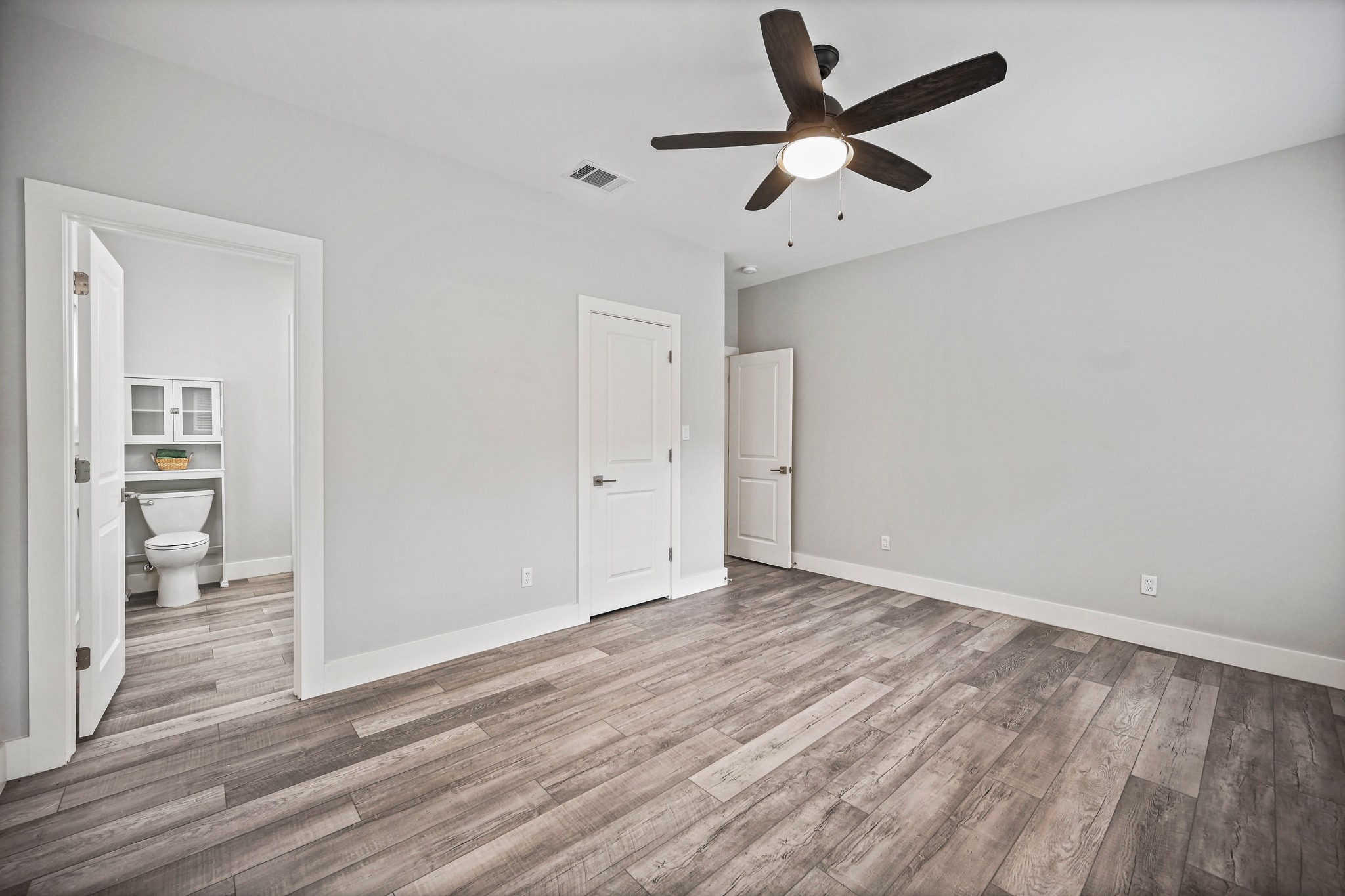 231 North Rainbow Ranch Road Wimberley, TX 78676 - Photo 18 of 40 Wood plank flooring and a ceiling fan complete this comfortable bedroom space.