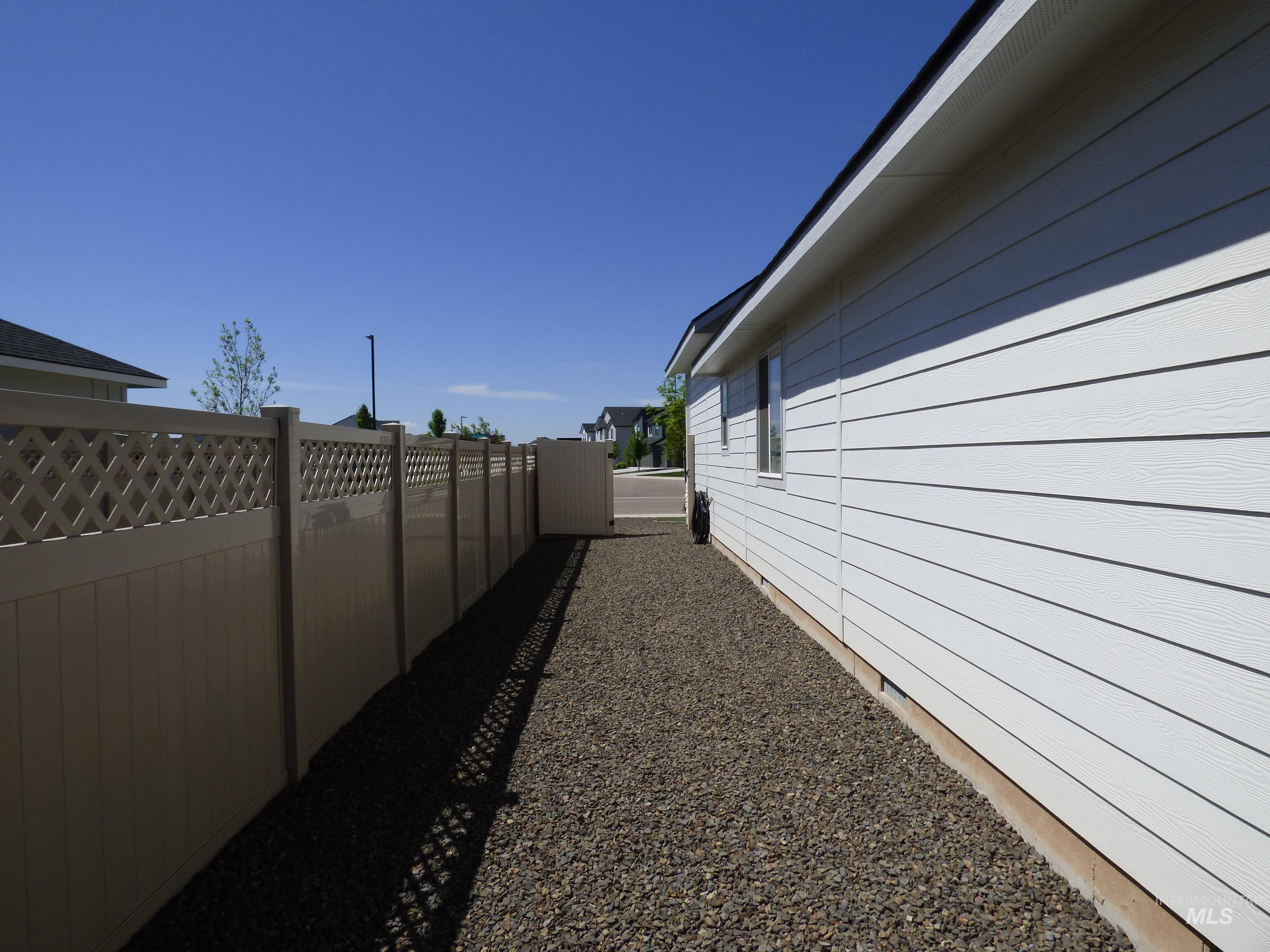 2708 East Buckaroo Drive Kuna, ID 83634 - Photo 45 of 48 Side yard featuring white horizontal siding, gravel landscaping, and a tan privacy fence with lattice top