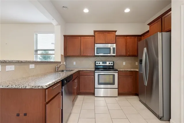 a kitchen with stainless steel appliances granite countertop a refrigerator sink and stove