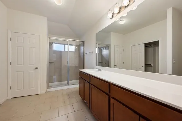 a spacious bathroom with a shower a sink and a mirror