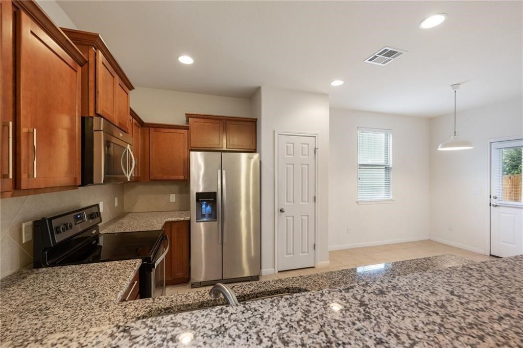 5428 Falling Leaf Lane, Unit 87 Austin, TX 78744 - Photo 8 of 31 a kitchen with stainless steel appliances kitchen island granite countertop a refrigerator and a stove top oven