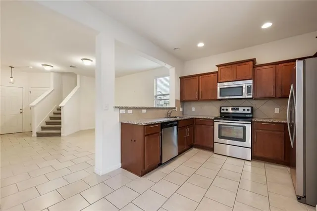 a kitchen with stainless steel appliances granite countertop a stove a sink and a microwave