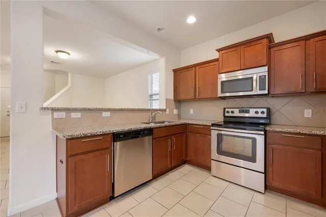 a kitchen with stainless steel appliances granite countertop a sink and a stove