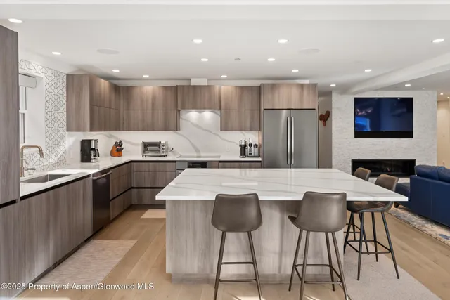 a large kitchen with stainless steel appliances kitchen island granite countertop a table and chairs in it