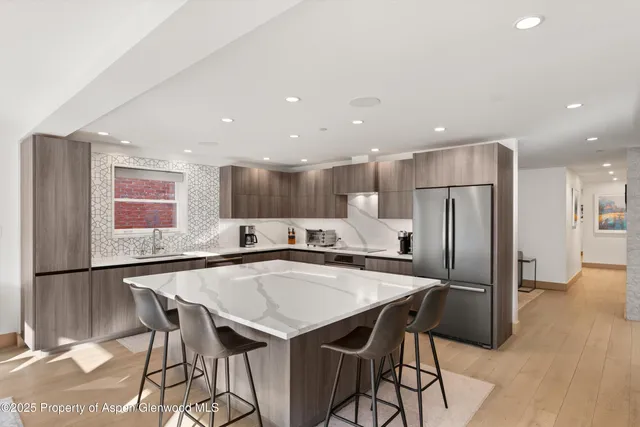 a living room with stainless steel appliances kitchen island granite countertop a table chairs and a view of living room