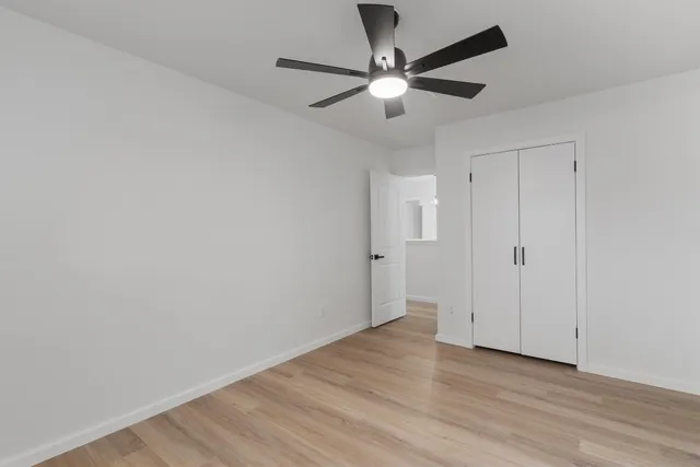 an empty room with wooden floor chandelier fan and closet area