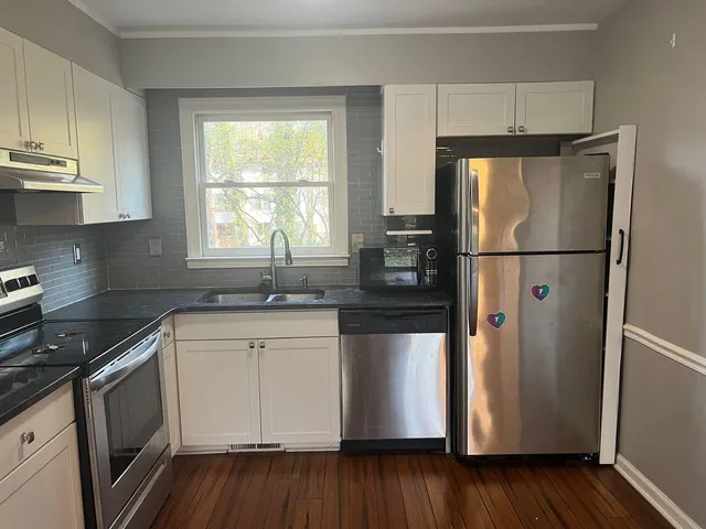 a kitchen with a refrigerator a sink and wooden floor