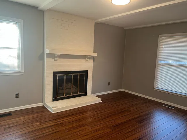 an empty room with wooden floor and fireplace