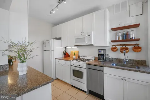 a kitchen with stainless steel appliances granite countertop a white refrigerator a sink a stove and white cabinets