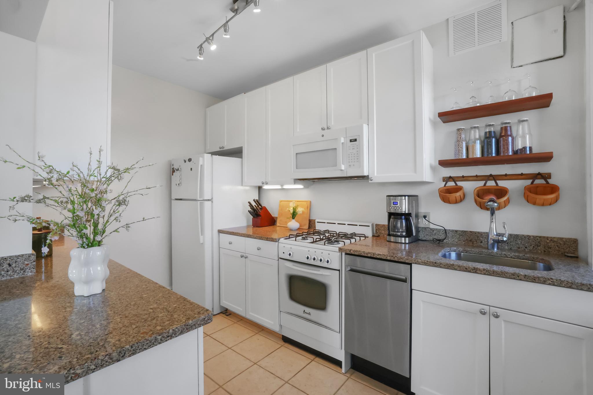 3446 Connecticut Avenue Northwest, Unit 502 Washington, DC 20008 - Photo 14 of 35 a kitchen with stainless steel appliances granite countertop a white refrigerator a sink a stove and white cabinets