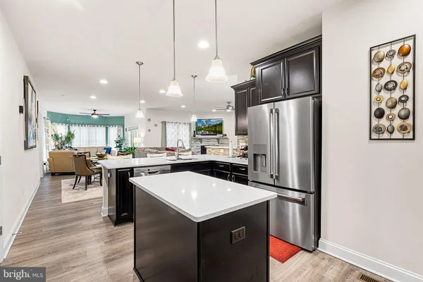 a kitchen with a sink a kitchen island wooden floor and stainless steel appliances