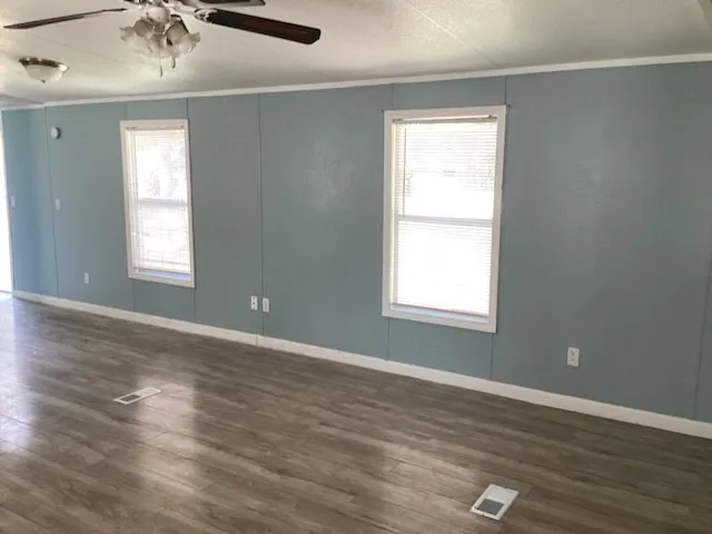 an empty room with wooden floor and windows