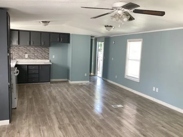 a view of an empty room with window and wooden floor
