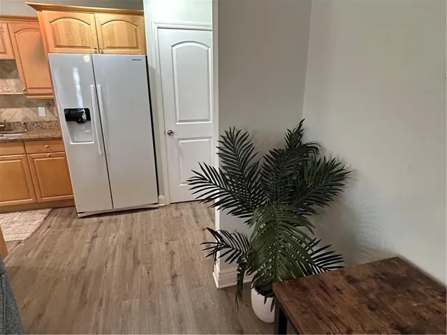 a kitchen with stainless steel appliances granite countertop a dining table chairs refrigerator and sink