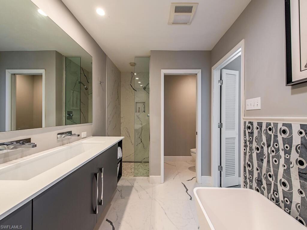 540 Rudder Road Naples, FL 34102 - Photo 9 of 12 a spacious bathroom with a bathtub sink and mirror