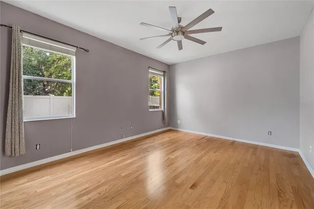 a view of an empty room with a window and wooden floor