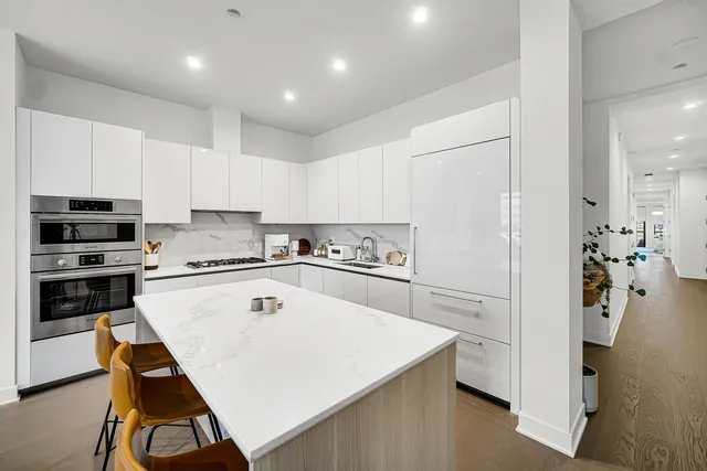 a white kitchen with wooden floor and stainless steel appliances